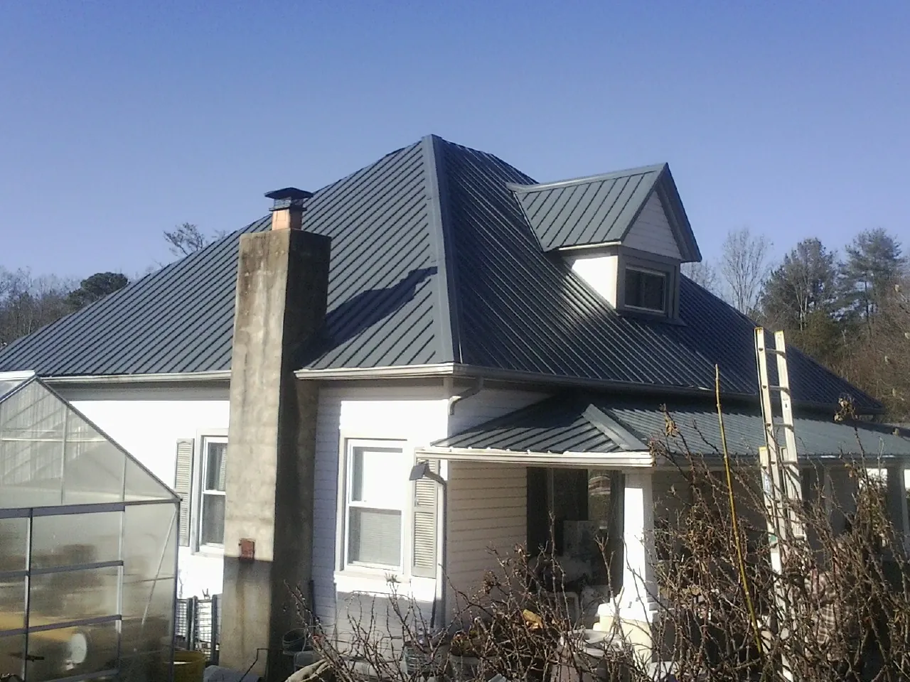 Dark blue standing seam metal roof on a white farmhouse with dormer — Slate & Tile Roof Repair by Roofing Brothers in Smartsville