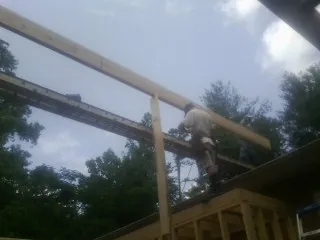 Carpenter setting a ridge beam over a new addition frame — Ice Dam Removal by Roofing Brothers in Smartsville