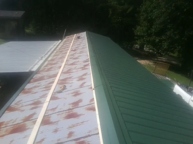 Old rusted panels beside newly installed green metal roofing — Wind Damage Roof Repair by Roofing Brothers in Smartsville