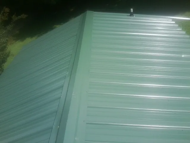 New green metal panels meeting at the ridge of a roof — Flat Roof Repair work by our crew in Smartsville