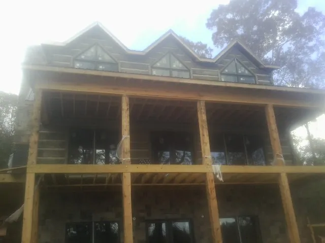 Dormers and porch framing on a large log home under construction — Roof Coating work by our crew in Smartsville