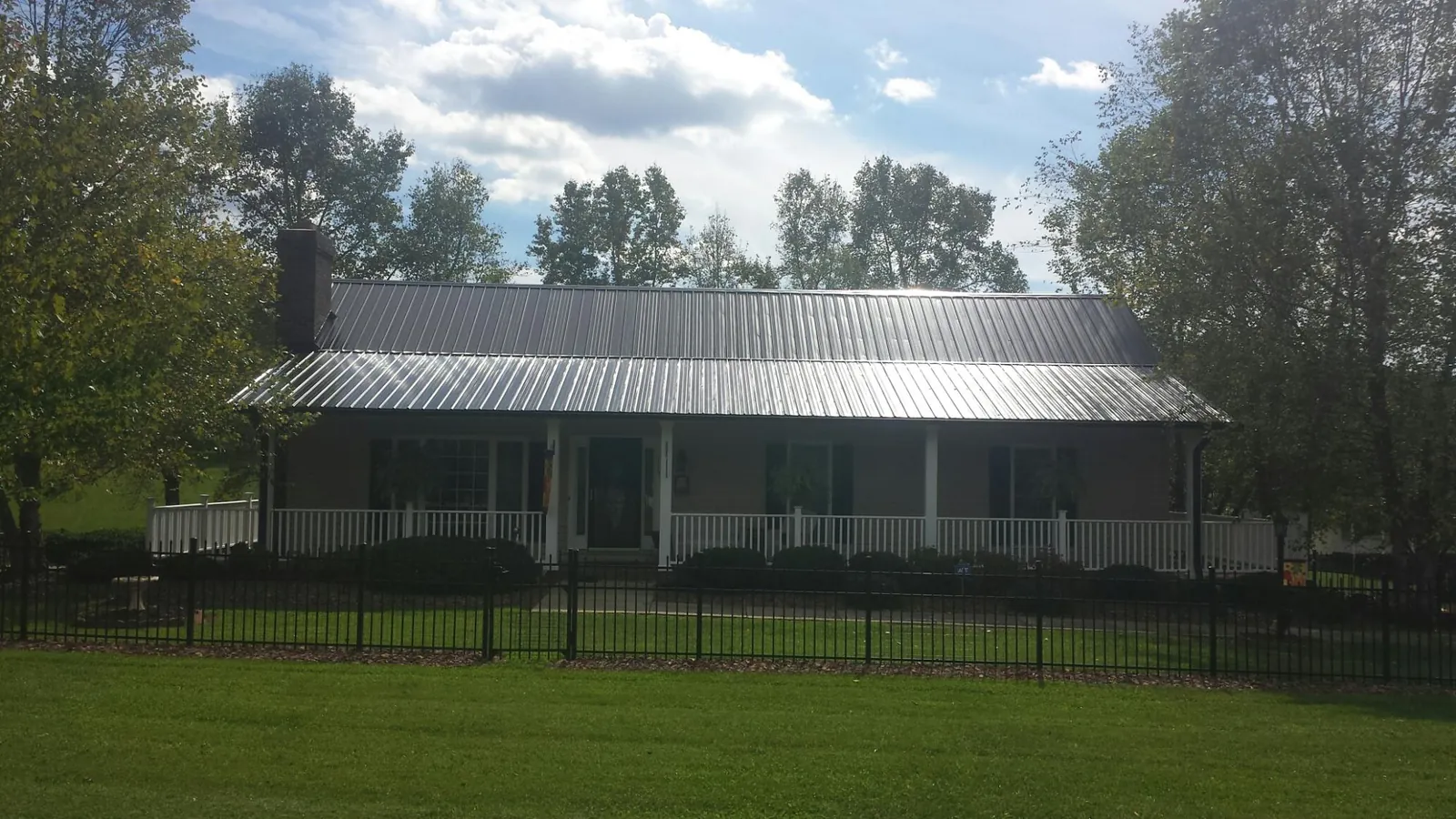 Gray metal roof on a brick ranch with a full width front porch — Gutter Guard Installation work by our crew in Smartsville