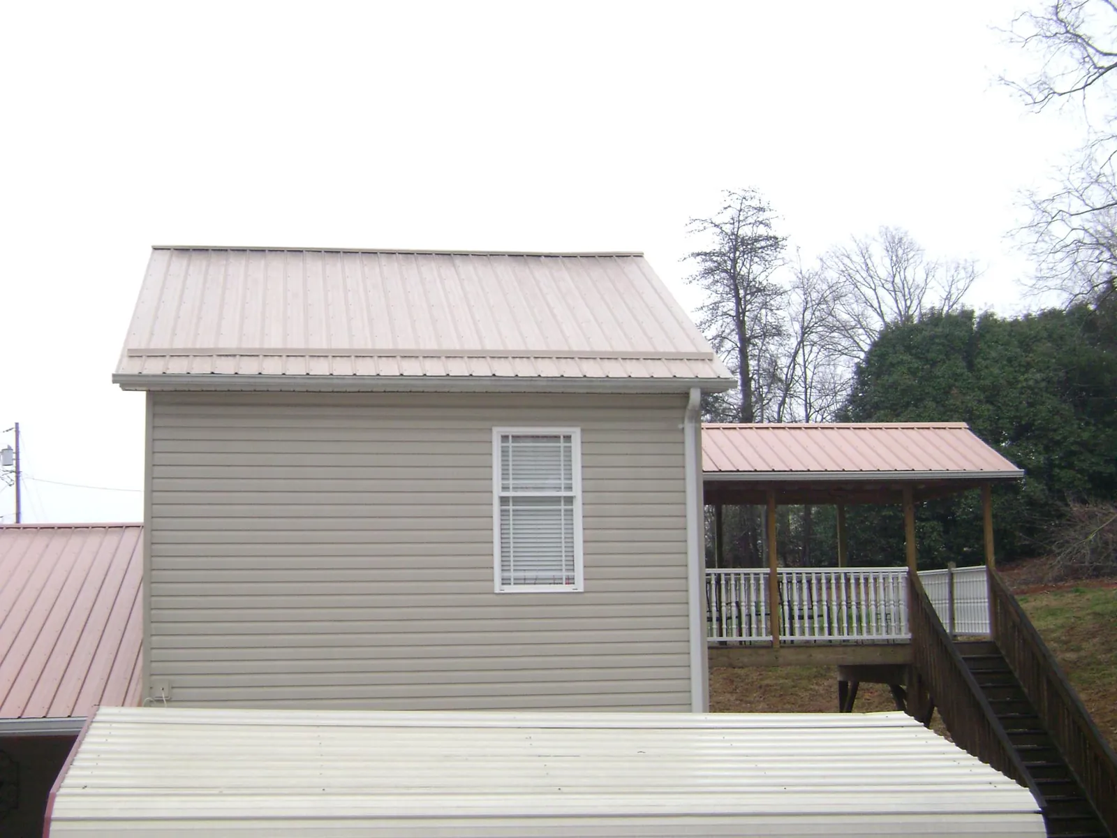 Tan metal roofs on a two story addition and attached porch, from a Roof Replacement job in Smartsville